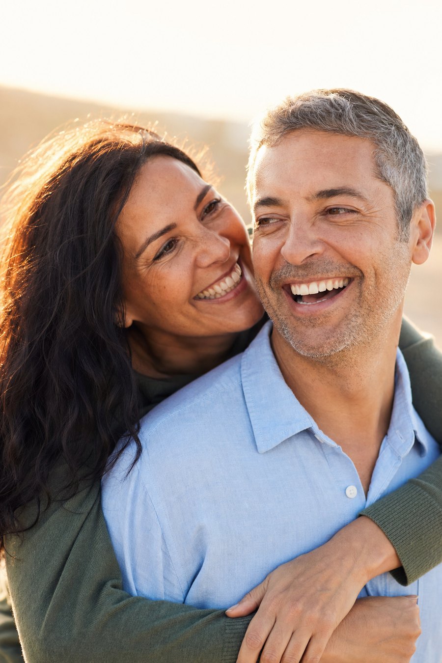 A smiling couple in their forties laughing together outdoors